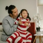 Storczyk po kwitnieniu: co dalej, by zakwitł ponownie? Ojciec i córka w pasiowych piżamach bawią się razem w salonie